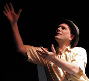 A man in a hat and shirt is holding his hands up