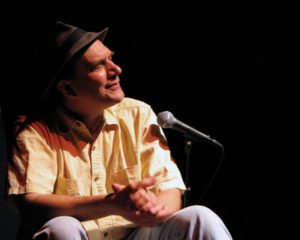 A man sitting on stage with a microphone.