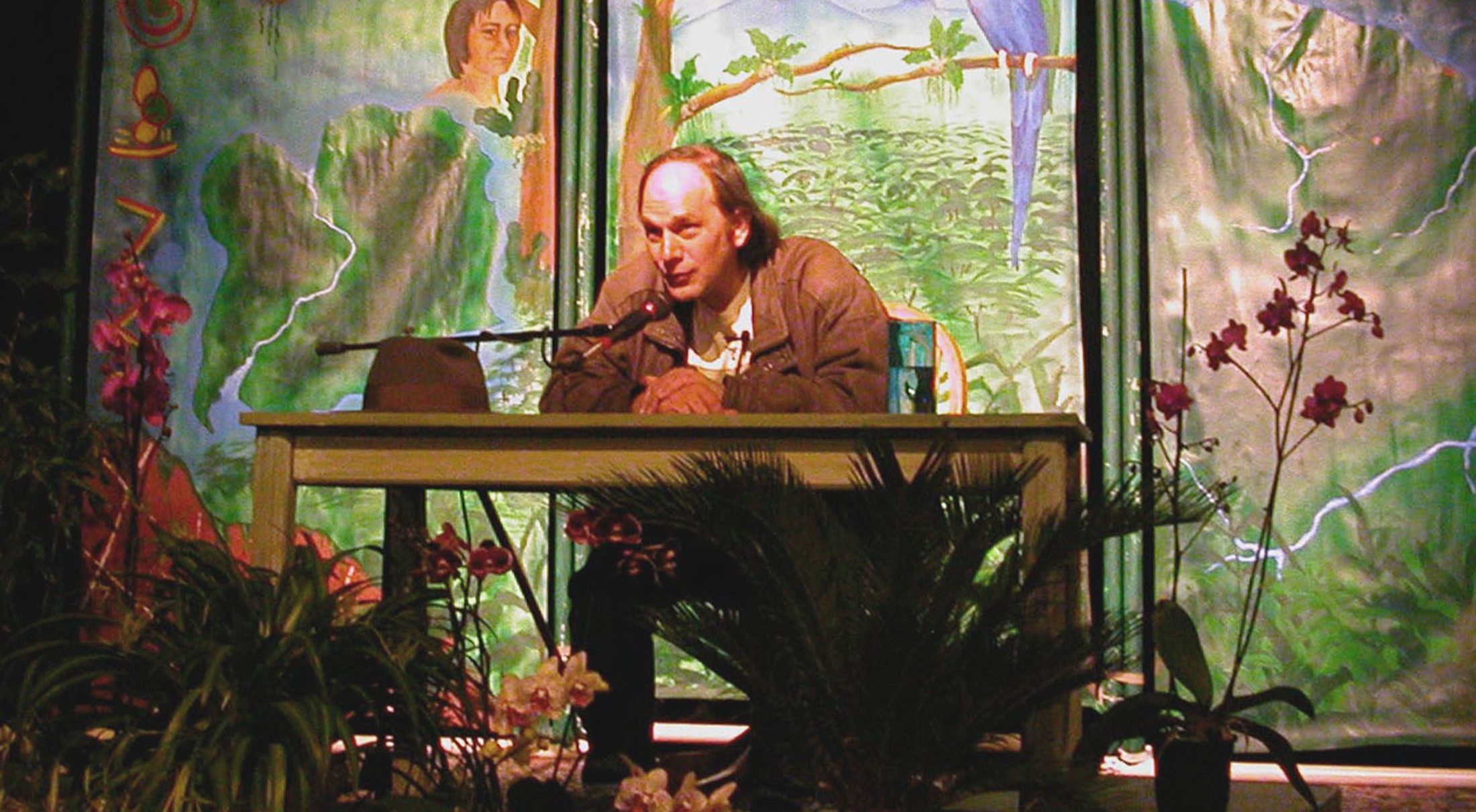 A man sitting at a table in front of a painting.