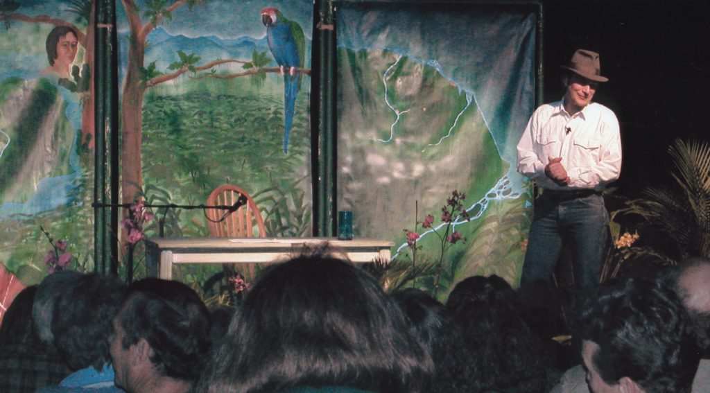 A man standing on stage with a parrot.
